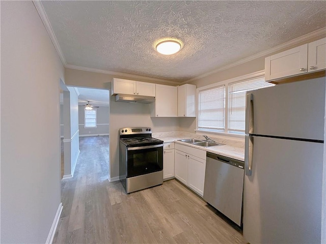 kitchen featuring appliances with stainless steel finishes, light countertops, under cabinet range hood, white cabinetry, and a sink