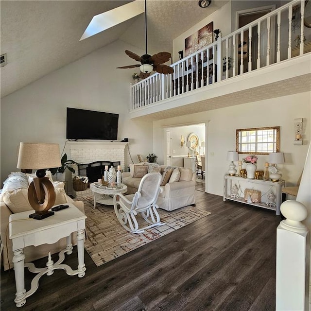 living room featuring a skylight, a brick fireplace, ceiling fan, high vaulted ceiling, and dark hardwood / wood-style floors