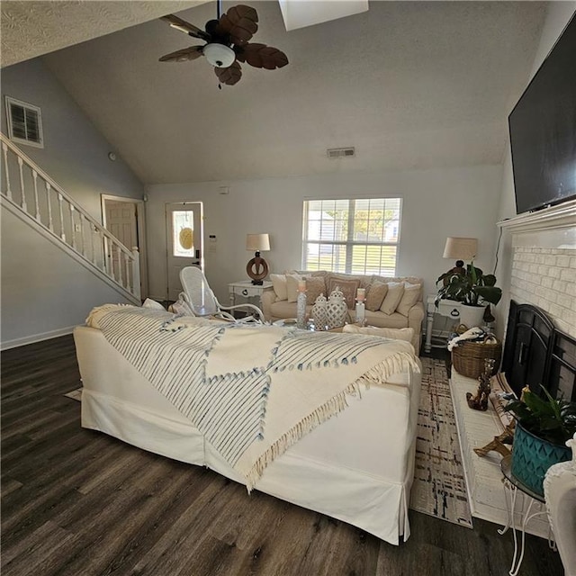 bedroom with dark hardwood / wood-style flooring, vaulted ceiling, a fireplace, and ceiling fan