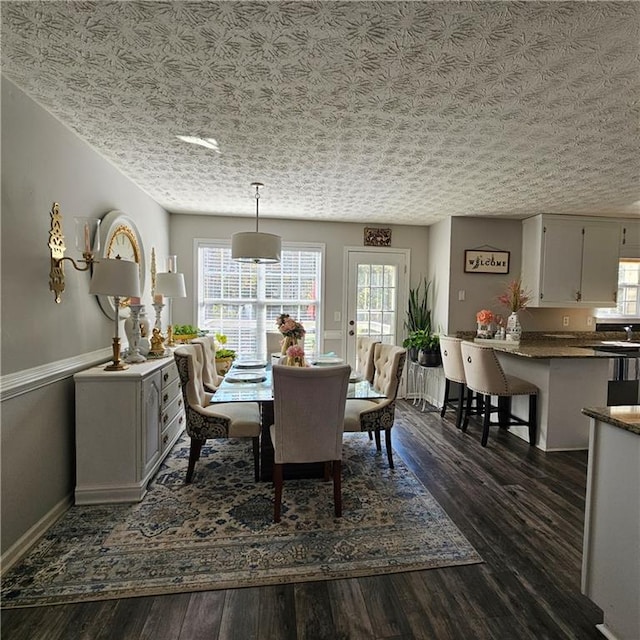 dining room with a textured ceiling and dark hardwood / wood-style floors