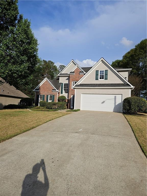 view of front of house featuring brick siding, driveway, a front yard, and a garage
