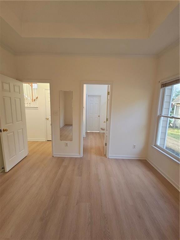spare room with light wood finished floors, a notable chandelier, baseboards, and a raised ceiling
