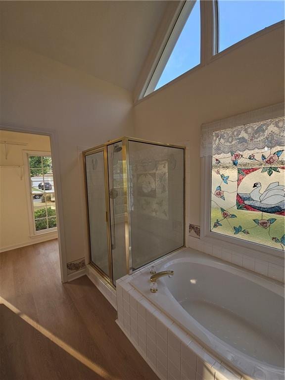 bathroom featuring a garden tub, high vaulted ceiling, wood finished floors, a stall shower, and baseboards