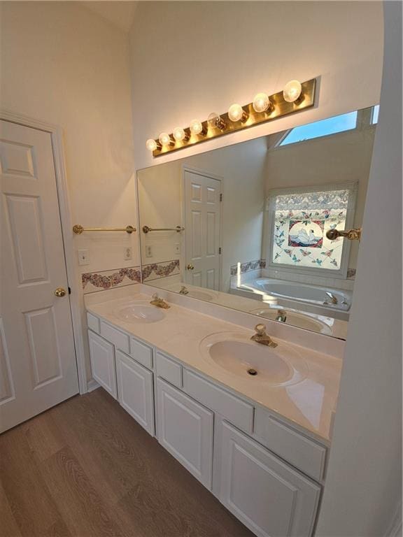 full bath featuring a garden tub, double vanity, and a sink