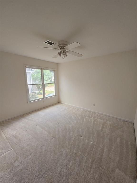spare room with light carpet, visible vents, baseboards, and a ceiling fan