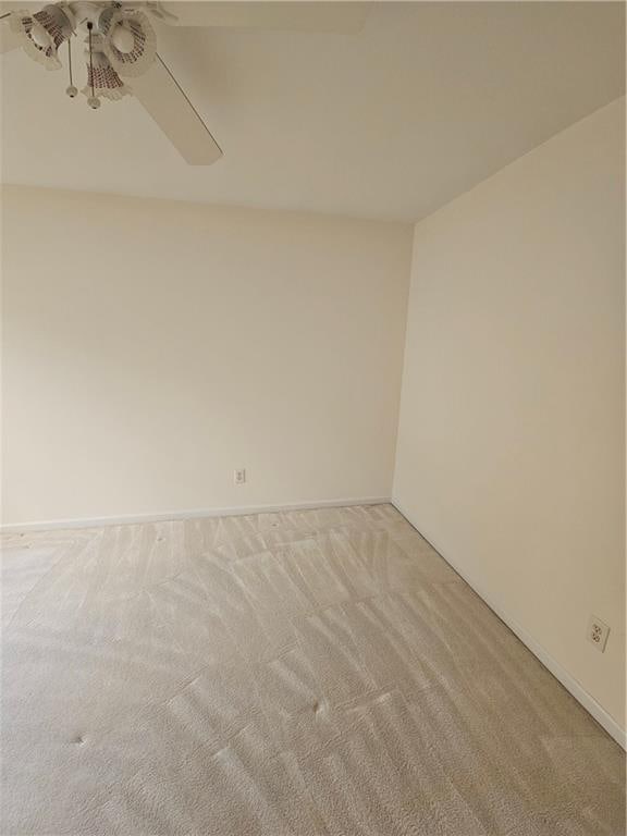 empty room featuring light carpet, baseboards, and ceiling fan