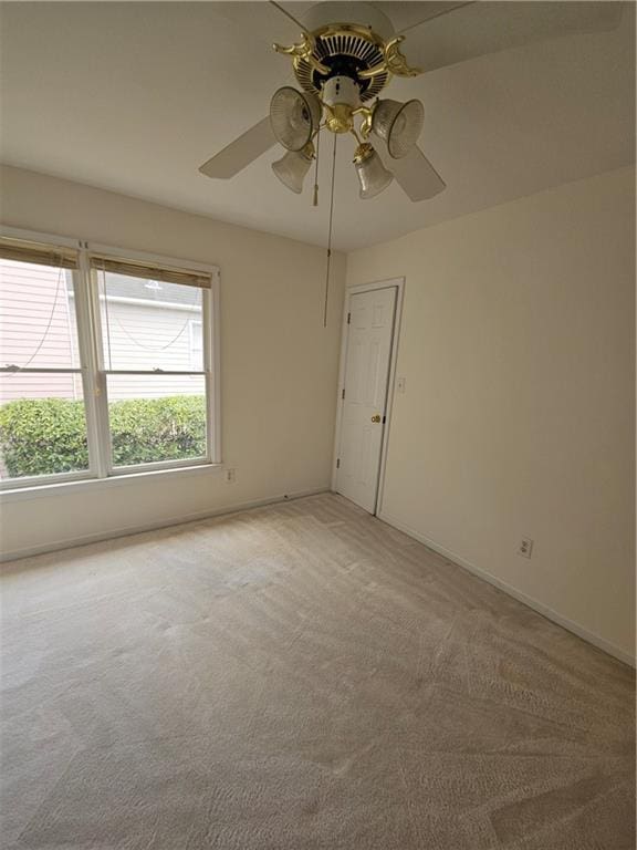 empty room featuring baseboards, a ceiling fan, and light carpet