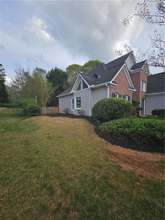 view of property exterior with brick siding and a lawn