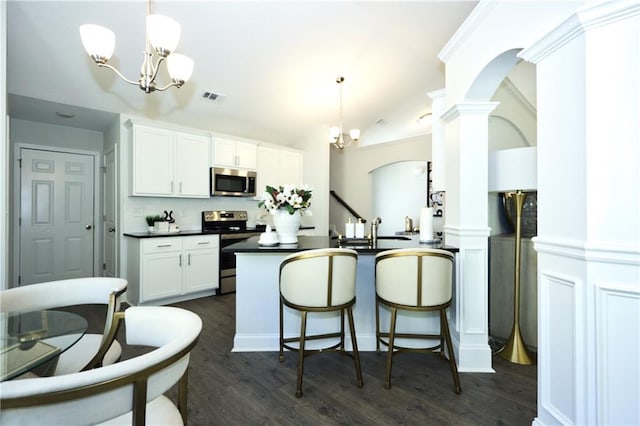 40 Eryn Ter, Covington, GA 30014 - kitchen featuring appliances with stainless steel finishes, a chandelier, dark countertops, dark wood finished floors, and white cabinets