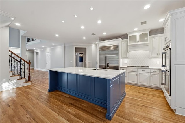 kitchen featuring a spacious island, white cabinetry, stainless steel appliances, and light hardwood / wood-style flooring