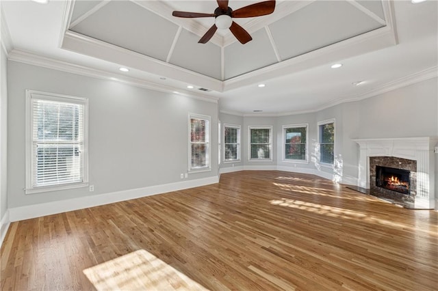 unfurnished living room featuring hardwood / wood-style flooring, crown molding, a healthy amount of sunlight, and a premium fireplace