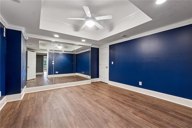 unfurnished room featuring ceiling fan, a raised ceiling, wood-type flooring, and crown molding