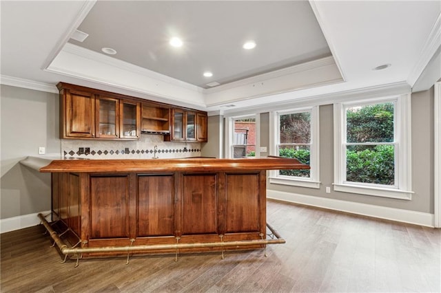 bar with hardwood / wood-style flooring, a raised ceiling, and crown molding