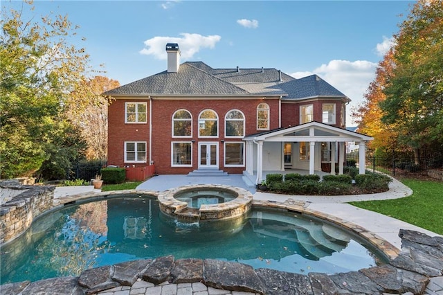 rear view of property featuring a pool with hot tub, a patio, and french doors