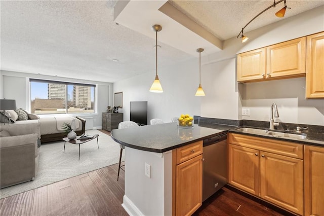 kitchen featuring dark wood-type flooring, sink, decorative light fixtures, stainless steel dishwasher, and kitchen peninsula