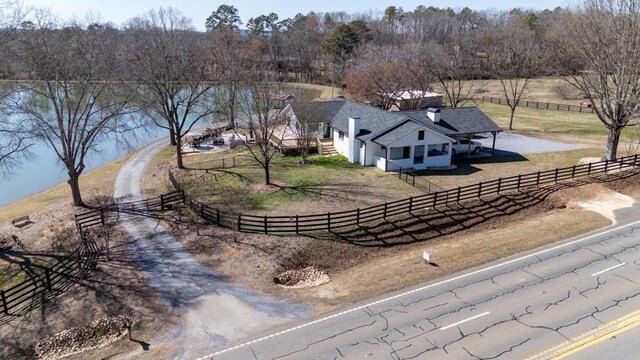 view of front facade with dirt driveway, a carport, and a chimney