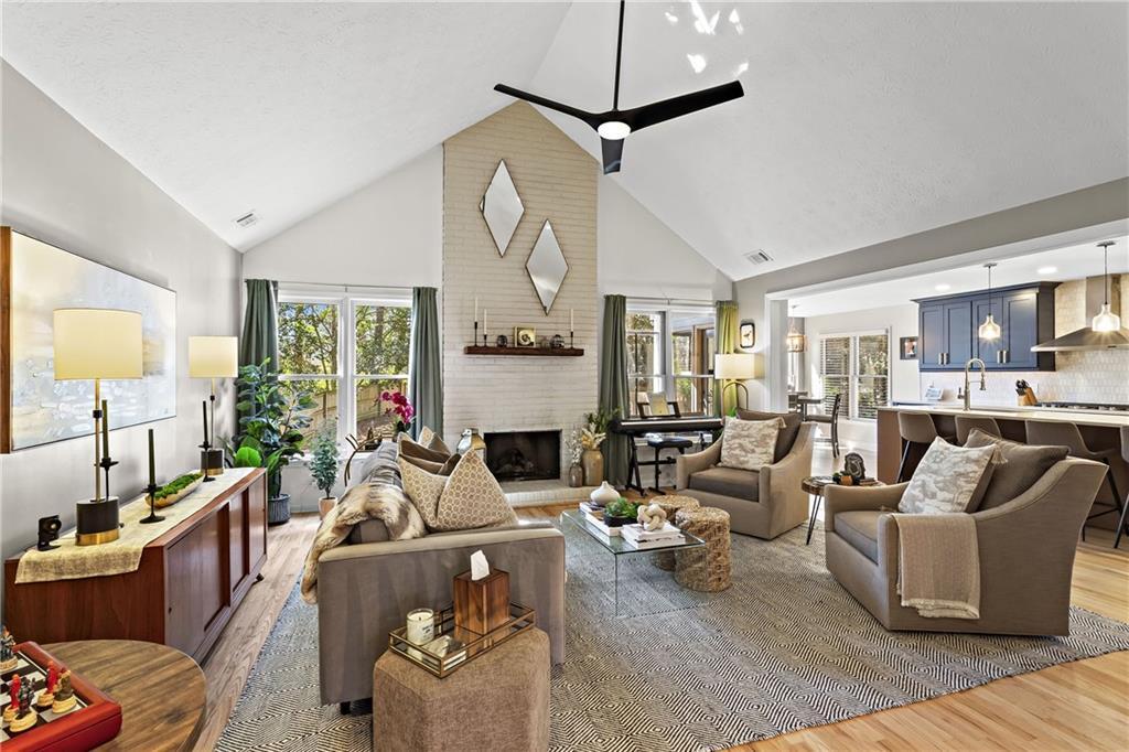living room with high vaulted ceiling, a healthy amount of sunlight, wood finished floors, and a fireplace