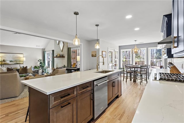 kitchen with a sink, stainless steel appliances, light wood-style floors, and light countertops