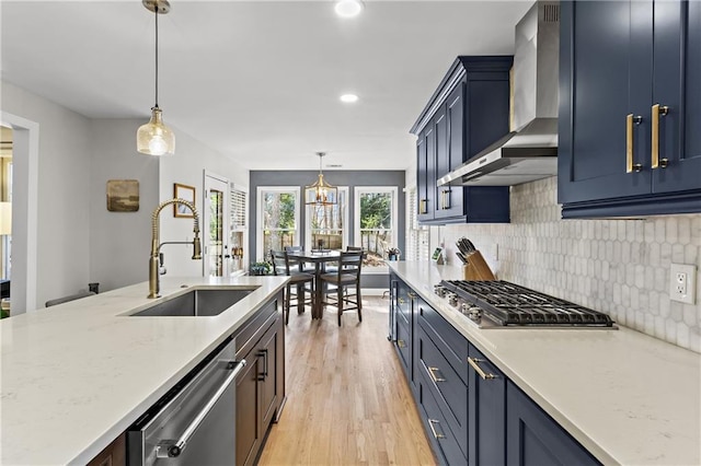 kitchen featuring a sink, decorative backsplash, appliances with stainless steel finishes, and wall chimney exhaust hood