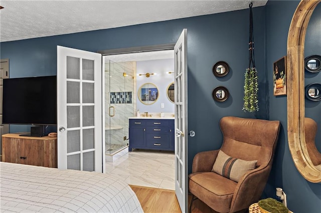 bedroom with connected bathroom, french doors, marble finish floor, and a textured ceiling