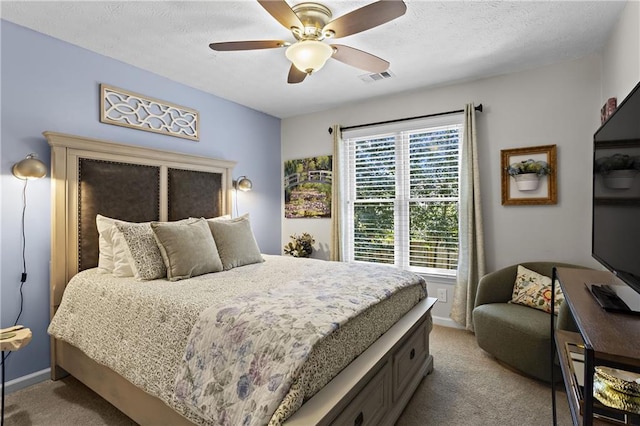 bedroom with a textured ceiling, ceiling fan, visible vents, and light carpet