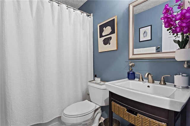 bathroom featuring a textured ceiling, toilet, and vanity