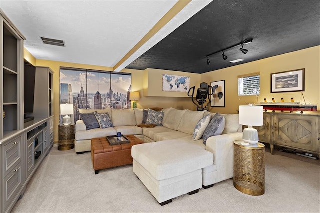 living area with visible vents, light colored carpet, rail lighting, and a textured ceiling