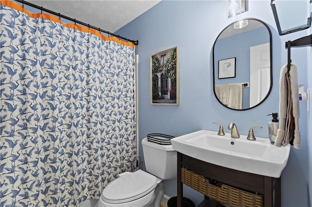 bathroom featuring a sink, a shower with shower curtain, toilet, and a textured ceiling