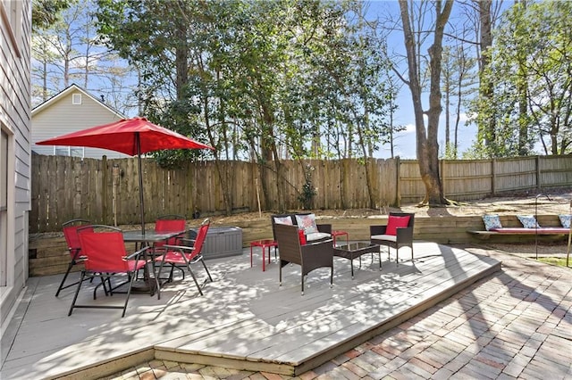 view of patio with outdoor dining area, a deck, a fenced backyard, and an outdoor hangout area