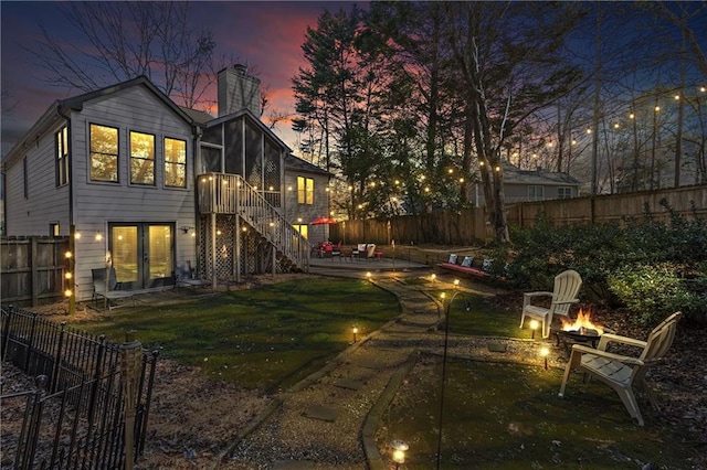 back of property featuring a patio, an outdoor fire pit, a fenced backyard, a sunroom, and stairs