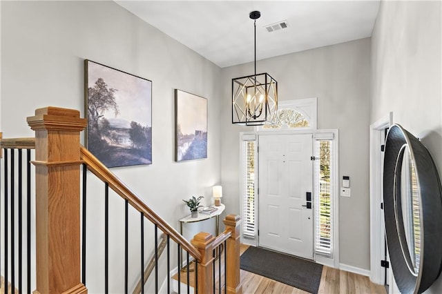 entryway featuring baseboards, visible vents, a chandelier, and light wood-type flooring