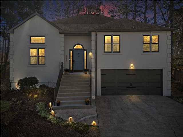 view of front of property featuring stucco siding, driveway, a shingled roof, and a garage