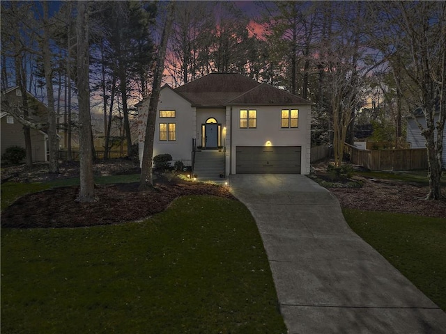 view of front of property with stucco siding, a lawn, fence, concrete driveway, and an attached garage