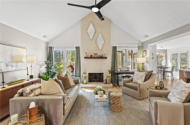 living room with visible vents, a brick fireplace, wood finished floors, high vaulted ceiling, and a ceiling fan