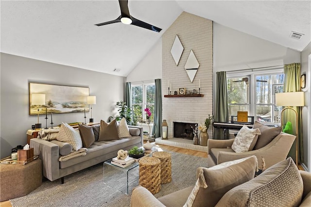 living room with visible vents, a fireplace, wood finished floors, high vaulted ceiling, and a ceiling fan