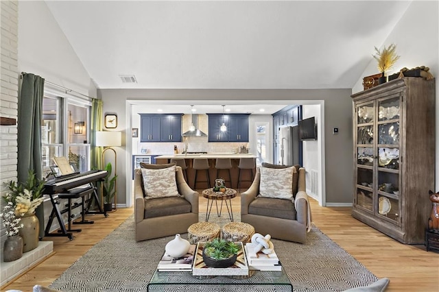 living area with light wood-type flooring, visible vents, lofted ceiling, and baseboards