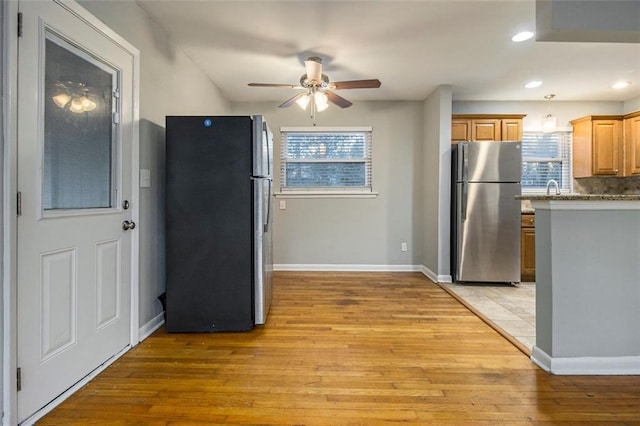 kitchen with backsplash, light hardwood / wood-style flooring, stainless steel refrigerator, and ceiling fan