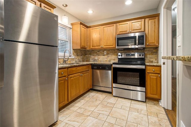 kitchen with pendant lighting, backsplash, sink, light stone counters, and stainless steel appliances