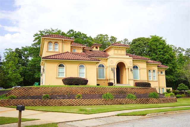 mediterranean / spanish home featuring a tiled roof and stucco siding