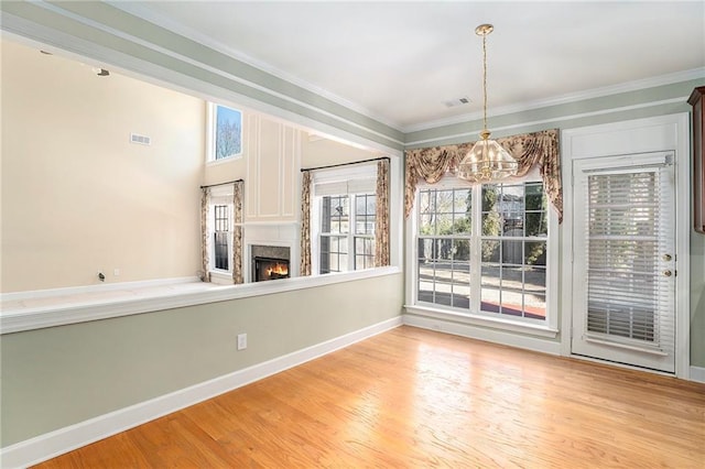 unfurnished dining area featuring visible vents, crown molding, a premium fireplace, and wood finished floors