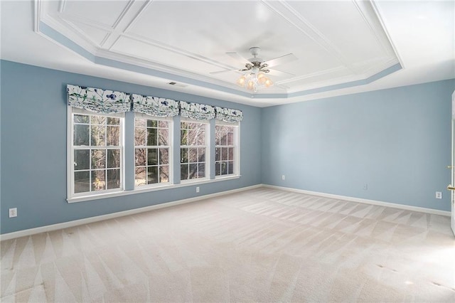 spare room featuring light carpet, a ceiling fan, baseboards, ornamental molding, and a tray ceiling