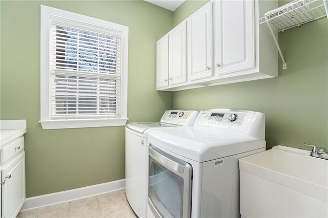 laundry room featuring cabinet space, baseboards, separate washer and dryer, a sink, and light tile patterned flooring