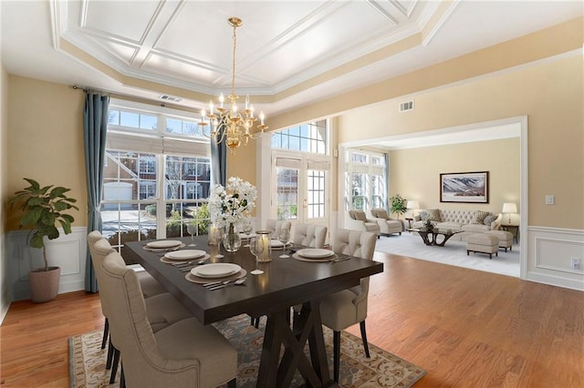 dining area with visible vents, wainscoting, light wood-style flooring, crown molding, and a chandelier