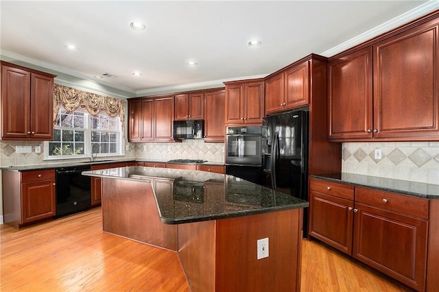 kitchen with a kitchen island, a sink, dark stone counters, black appliances, and light wood finished floors