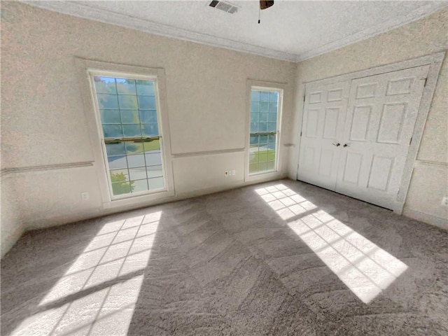 unfurnished bedroom with ceiling fan, ornamental molding, a textured ceiling, and light colored carpet