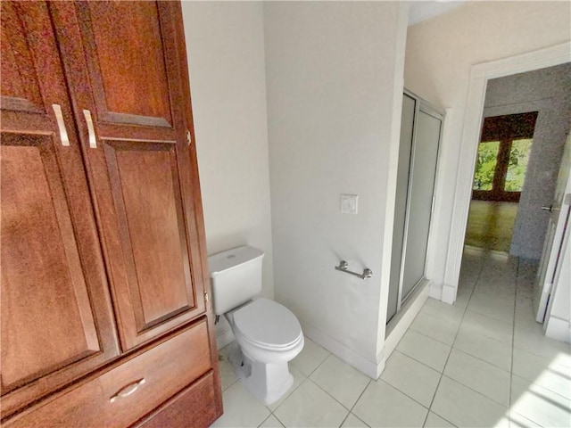 bathroom with a shower with door, tile patterned floors, and toilet