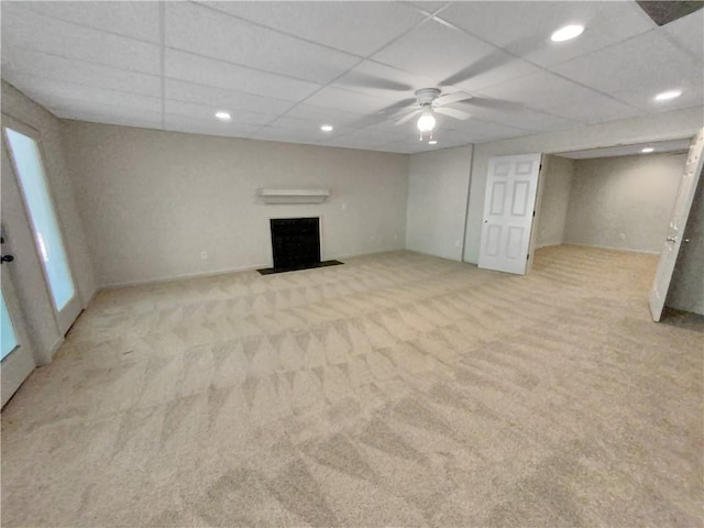 basement with ceiling fan, a drop ceiling, and light colored carpet