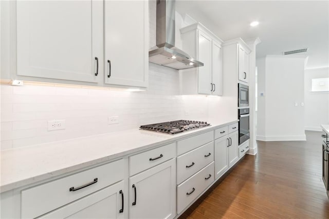 kitchen featuring stainless steel appliances, wall chimney exhaust hood, white cabinets, decorative backsplash, and dark hardwood / wood-style floors