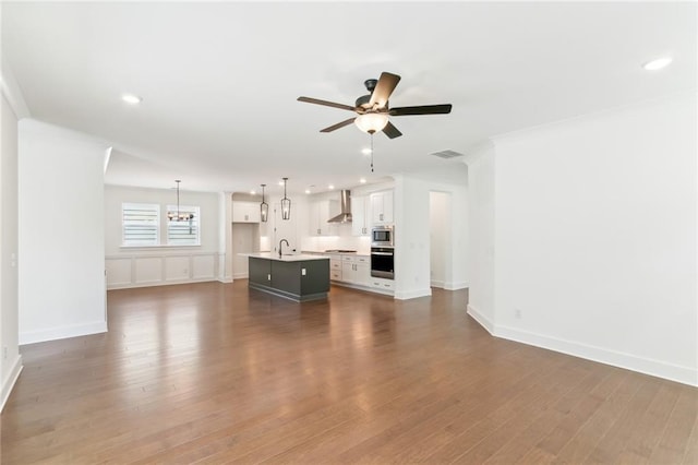 unfurnished living room with ornamental molding, dark hardwood / wood-style floors, sink, and ceiling fan with notable chandelier