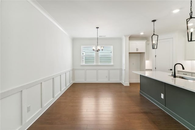 kitchen with dark hardwood / wood-style floors, sink, a notable chandelier, decorative light fixtures, and white cabinets